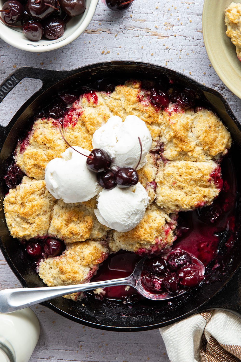 This cherry cobbler features a juicy fresh cherry filling baked with flaky browned butter biscuits on top. An incredible summer dessert warm from the oven with vanilla ice cream on top!