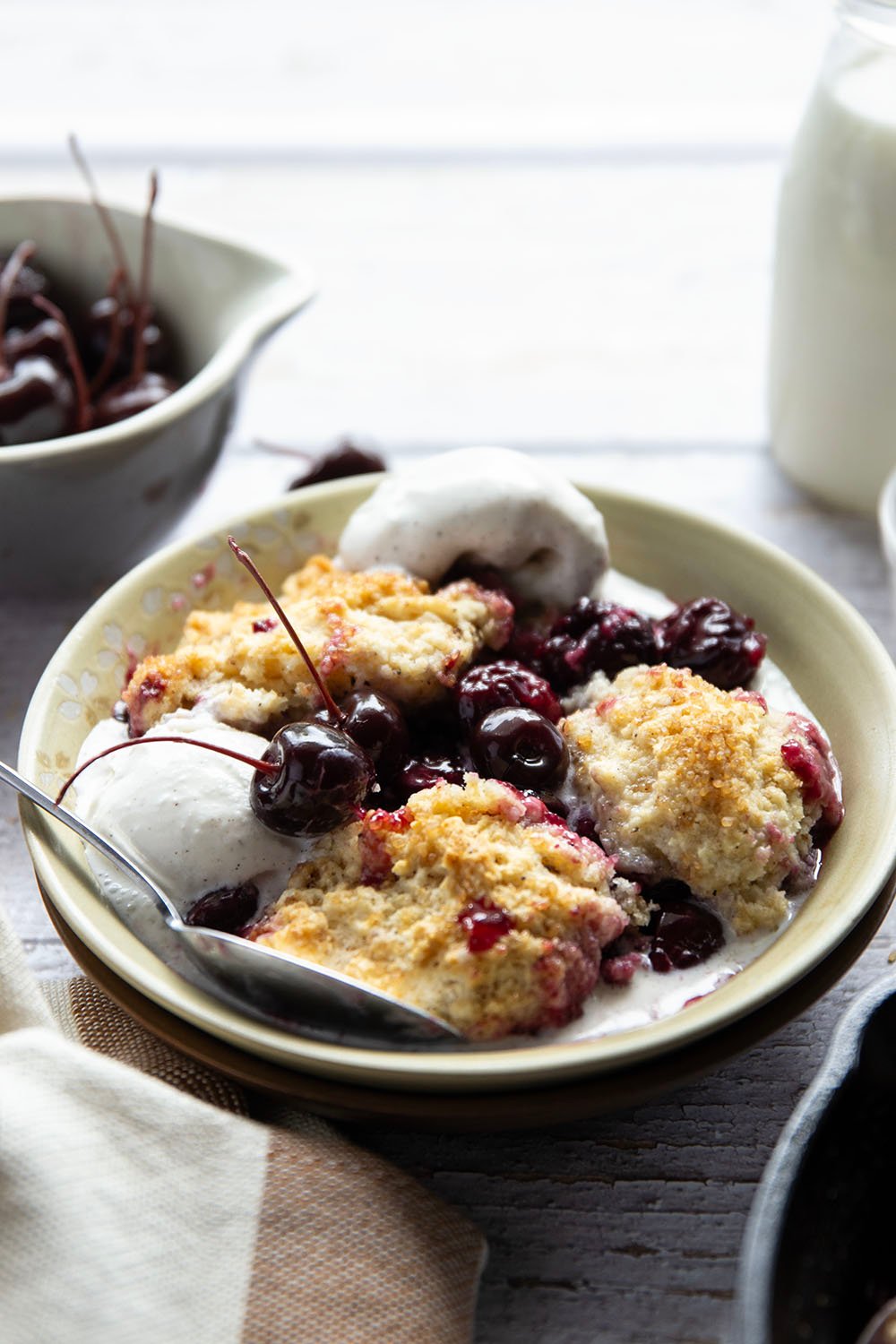 This cherry cobbler features a juicy fresh cherry filling baked with flaky browned butter biscuits on top. An incredible summer dessert warm from the oven with vanilla ice cream on top!
