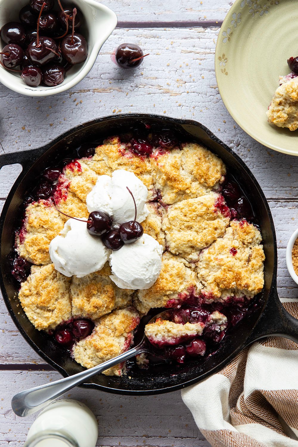 This cherry cobbler features a juicy fresh cherry filling baked with flaky browned butter biscuits on top. An incredible summer dessert warm from the oven with vanilla ice cream on top!