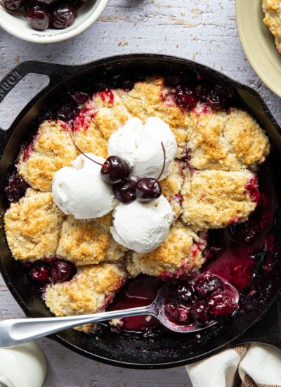 This cherry cobbler features a juicy fresh cherry filling baked with flaky browned butter biscuits on top. An incredible summer dessert warm from the oven with vanilla ice cream on top!