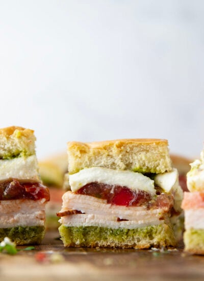 These caprese sliders feature herby basil pesto, sliced turkey, creamy burrata, and lots of fresh tomato slices layered between soft slider buns.