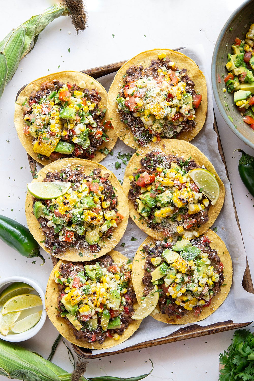 Creamy smashed black beans and a smoky grilled corn avocado salsa are piled onto these massively flavorful black bean tostadas for an easy vegetarian or vegan meal.