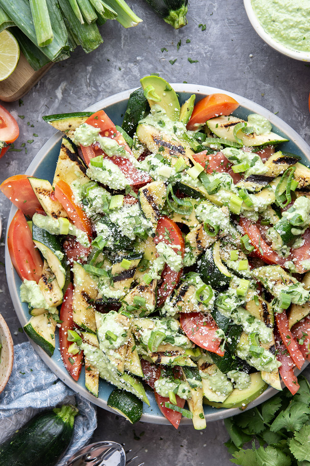 Tender zucchini is grilled until smoky and tossed with juicy summer tomatoes and a creamy avocado scallion dressing in this  flavor-packed zucchini tomato salad.