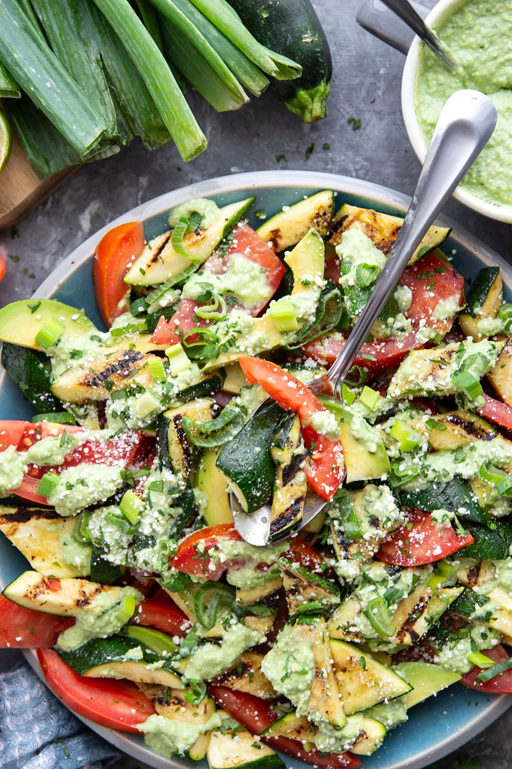 Tender zucchini is grilled until smoky and tossed with juicy summer tomatoes and a creamy avocado scallion dressing in this  flavor-packed zucchini tomato salad.