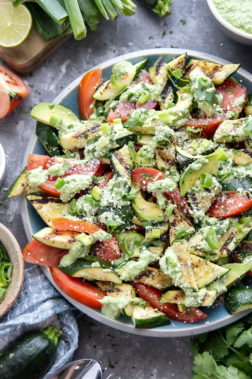 Tender zucchini is grilled until smoky and tossed with juicy summer tomatoes and a creamy avocado scallion dressing in this  flavor-packed zucchini tomato salad.
