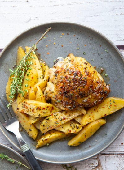 Baked alongside tender fall apples in a sweet and spicy chili maple glaze, these maple chicken thighs are a quick and flavorful fall dinner for any occasion.