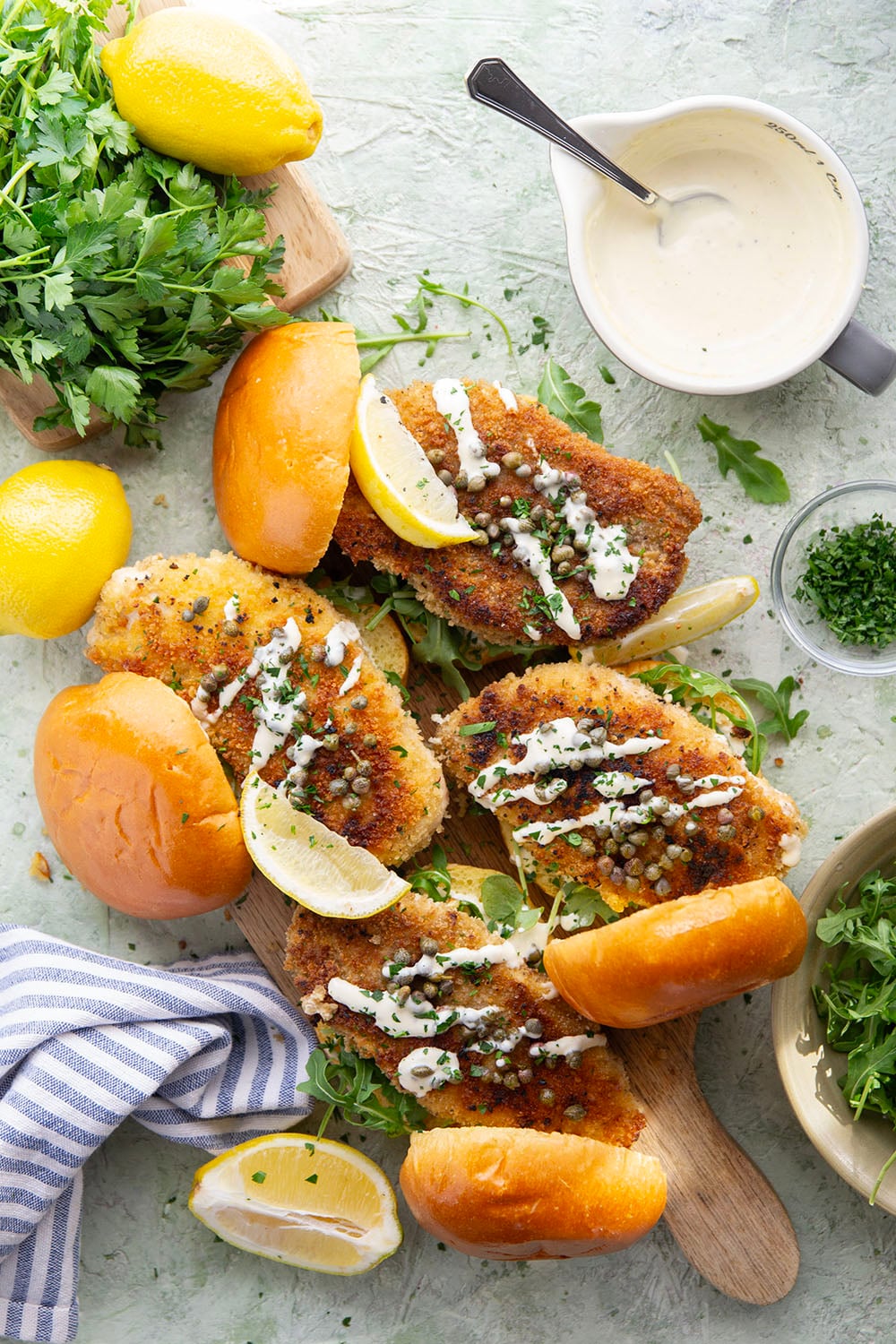 This chicken piccata sandwich feature all the things you love about classic chicken piccata in sandwich form! Fluffy brioche buns with crispy chicken cutlets squeezed with fresh lemon, tangy capers, peppery argula, and a creamy lemon aioli.