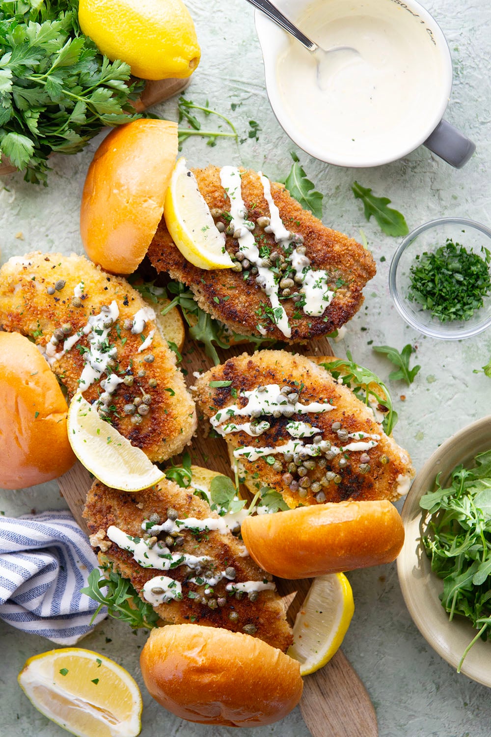 This chicken piccata sandwich feature all the things you love about classic chicken piccata in sandwich form! Fluffy brioche buns with crispy chicken cutlets squeezed with fresh lemon, tangy capers, peppery argula, and a creamy lemon aioli.