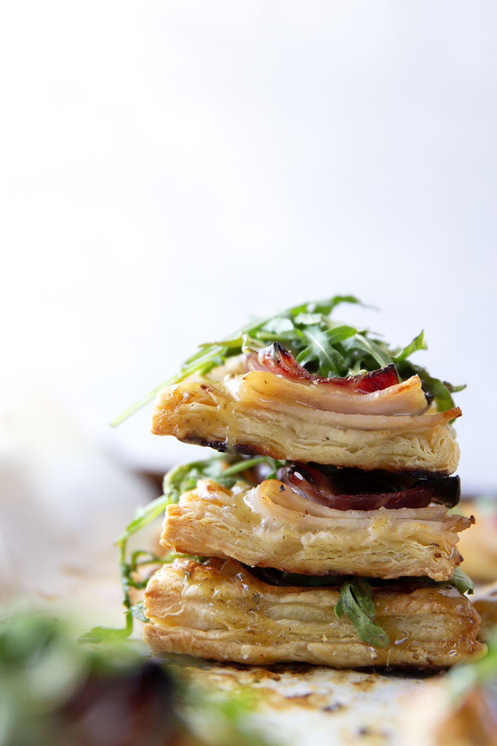 These savory cordon bleu puff pastry tarts have everything you'll find in the classic chicken dish in hand-held tart form! These tarts feature layers of deli ham, chicken, and Swiss cheese slices with a tangy honey mustard and lots of arugula piled on top.