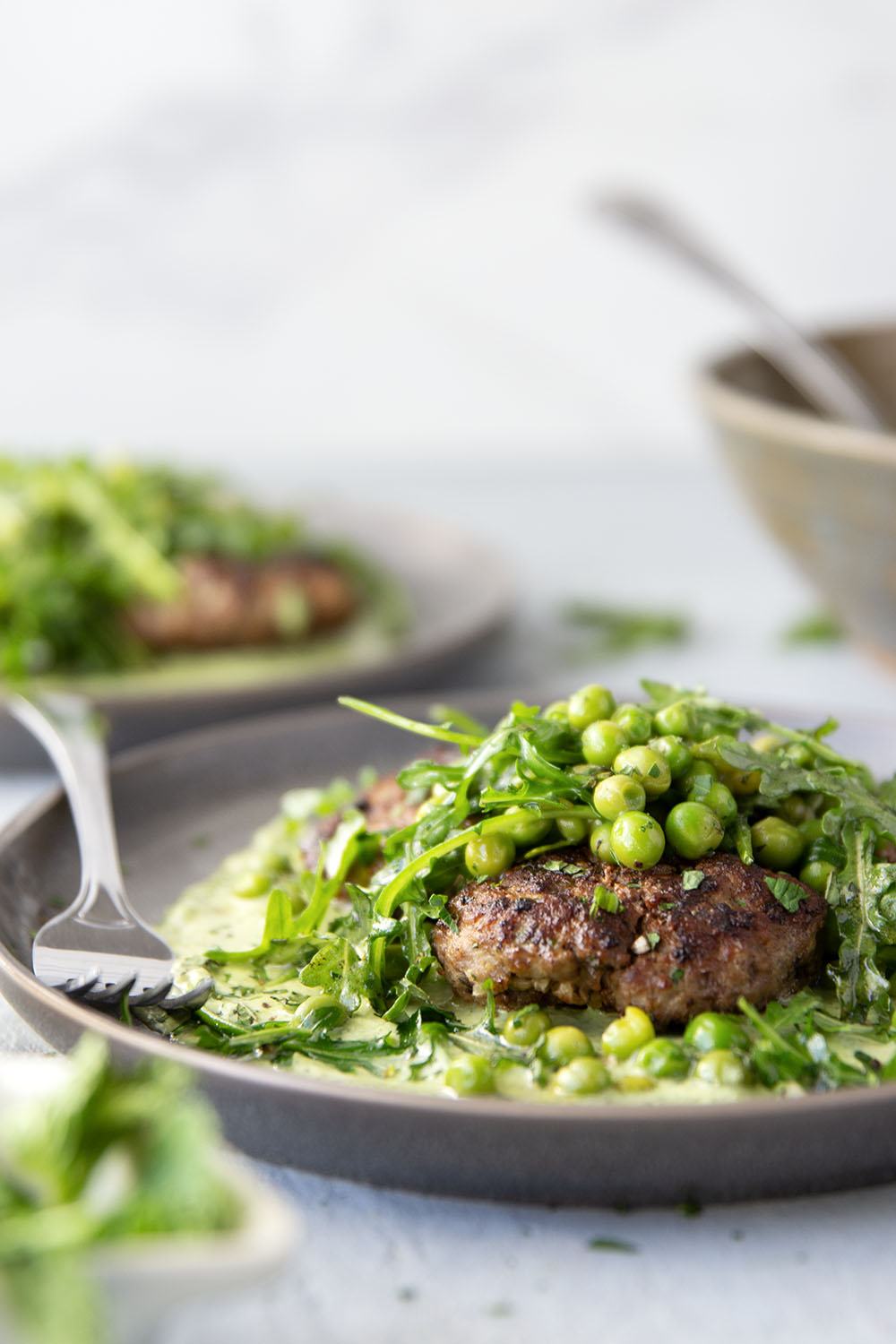 Juicy seared turkey patties are served on an herby green goddess sauce with lots of fresh arugula pea salad piled on top for a super fresh spring dinner.
