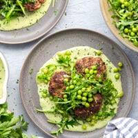 Juicy seared turkey patties are served on an herby green goddess sauce with lots of fresh arugula pea salad piled on top for a super fresh spring dinner.