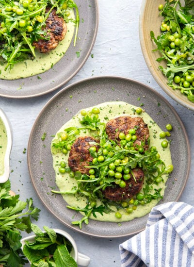 Juicy seared turkey patties are served on an herby green goddess sauce with lots of fresh arugula pea salad piled on top for a super fresh spring dinner.