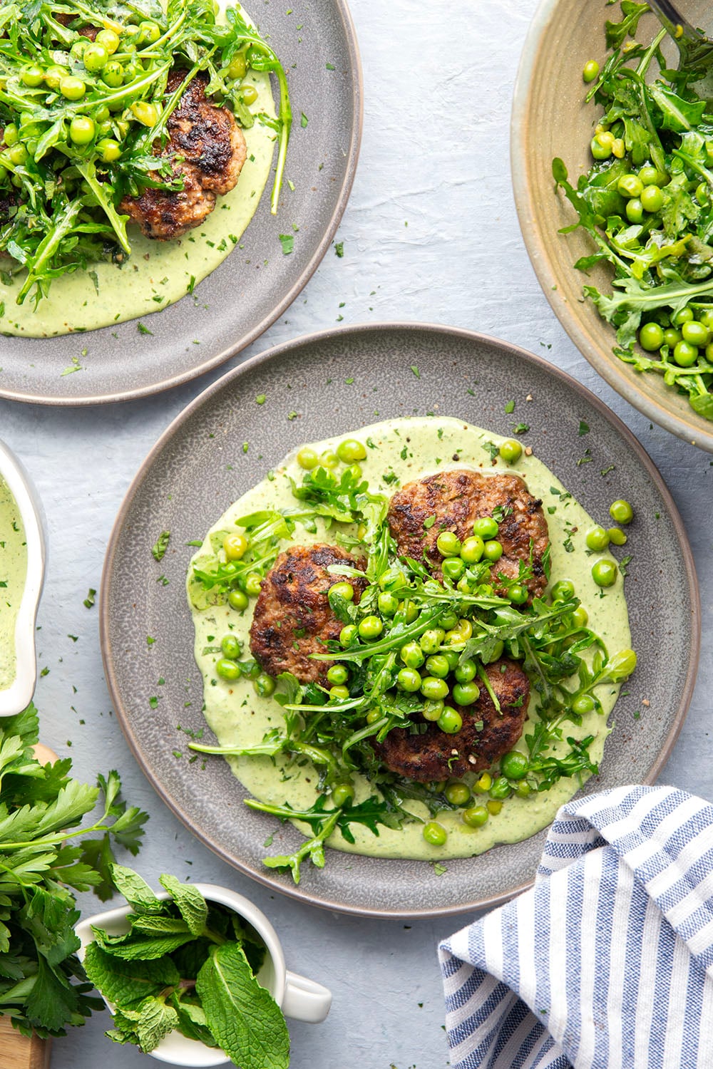 Juicy seared turkey patties are served on an herby green goddess sauce with lots of fresh arugula pea salad piled on top for a super fresh spring dinner.