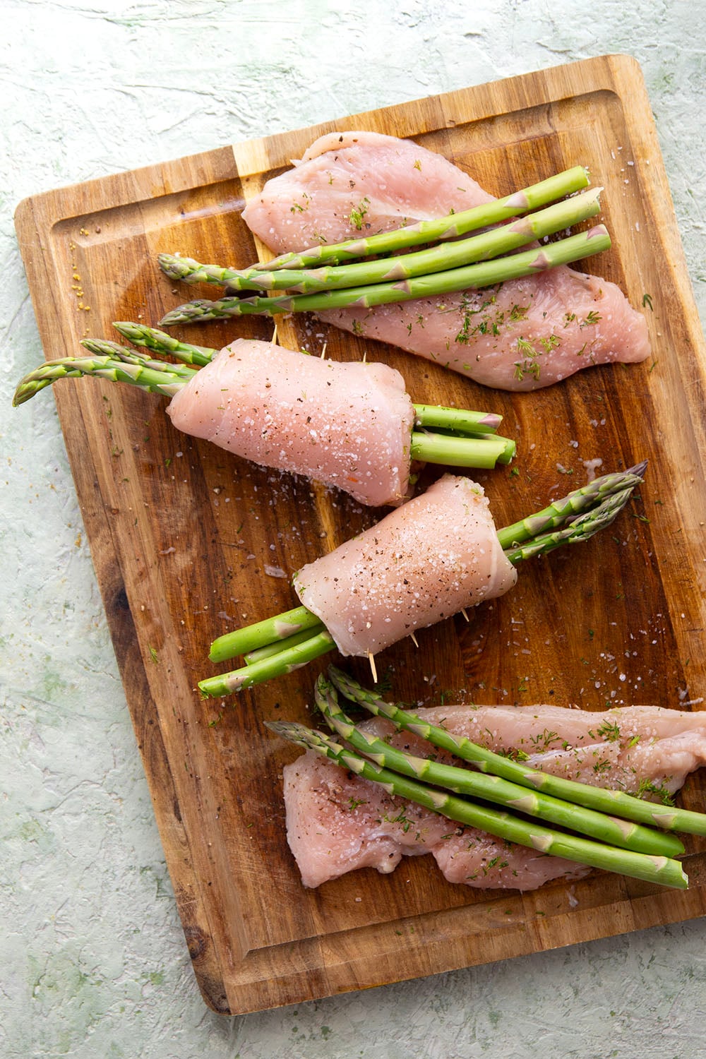 Asparagus chicken roll-ups feature chicken breast cutlets with tender asparagus spears rolled up inside and a garlicky lemon dill sauce spooned on top.