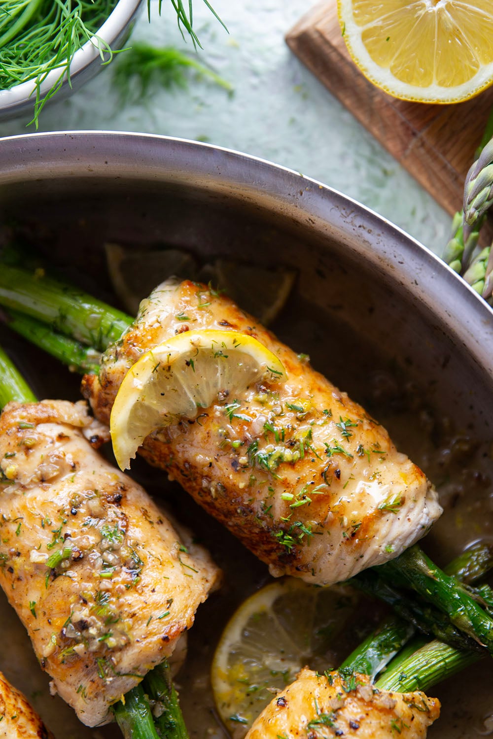 Asparagus chicken roll-ups feature chicken breast cutlets with tender asparagus spears rolled up inside and a garlicky lemon dill sauce spooned on top.