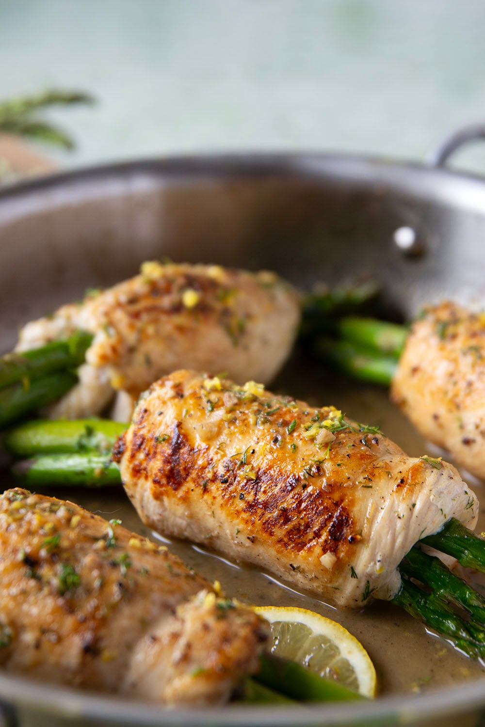 Asparagus chicken roll-ups feature chicken breast cutlets with tender asparagus spears rolled up inside and a garlicky lemon dill sauce spooned on top.