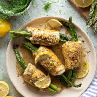 Asparagus chicken roll-ups feature chicken breast cutlets with tender asparagus spears rolled up inside and a garlicky lemon dill sauce spooned on top.