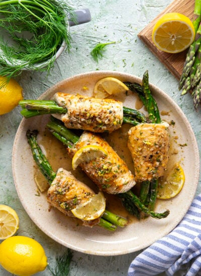 Asparagus chicken roll-ups feature chicken breast cutlets with tender asparagus spears rolled up inside and a garlicky lemon dill sauce spooned on top.