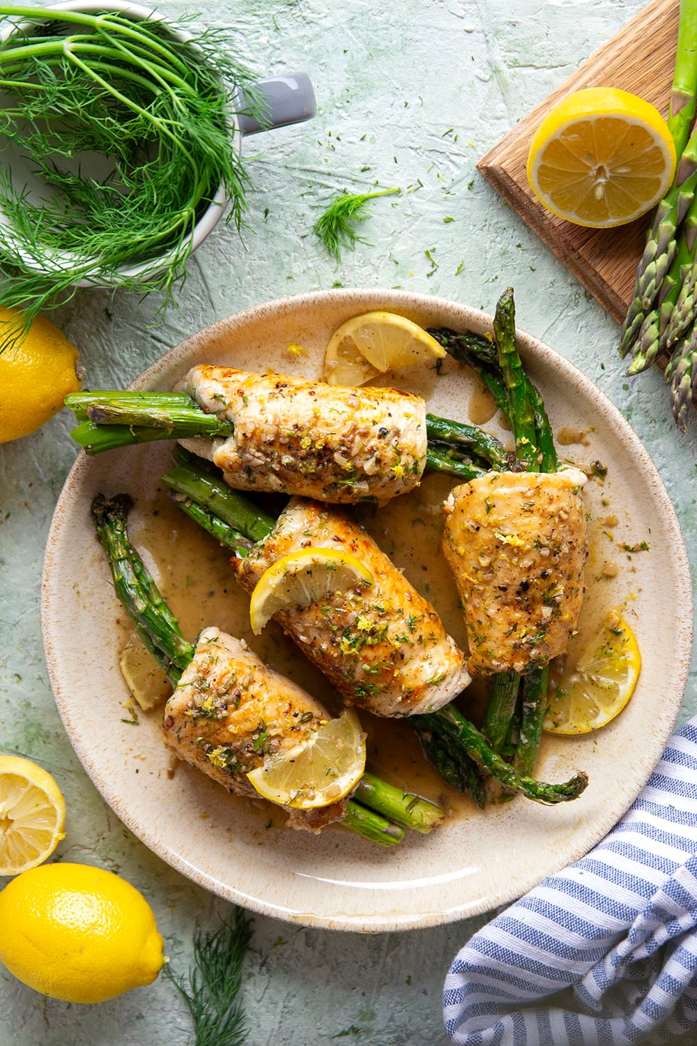 Asparagus chicken roll-ups feature chicken breast cutlets with tender asparagus spears rolled up inside and a garlicky lemon dill sauce spooned on top.