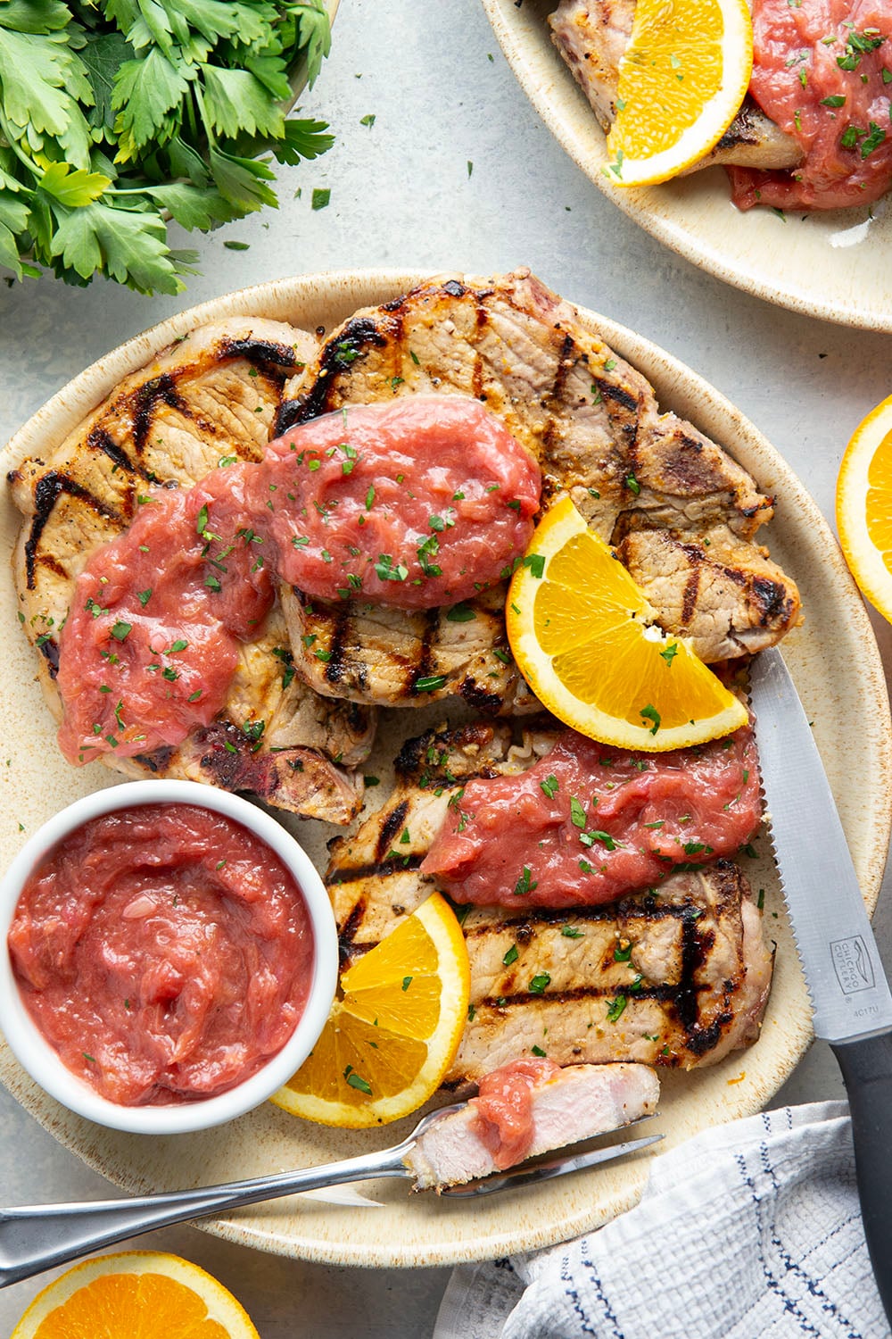 These grilled orange pork chops feature pork chops marinated in a fresh orange marinade, grilled until perfectly juicy, and served with a sweet and tangy rhubarb compote.