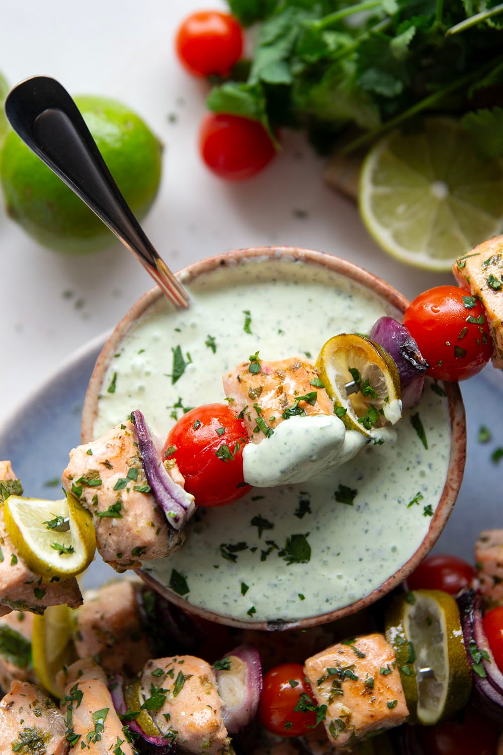 Marinated in a fresh cilantro lime sauce and grilled alongside red onion, cherry tomatoes, and served with a cilantro lime crema, these cilantro lime grilled salmon kabobs are a quick dinner to throw on the grill for any occasion.