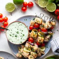 Marinated in a fresh cilantro lime sauce and grilled alongside red onion, cherry tomatoes, and served with a cilantro lime crema, these cilantro lime grilled salmon kabobs are a quick dinner to throw on the grill for any occasion.