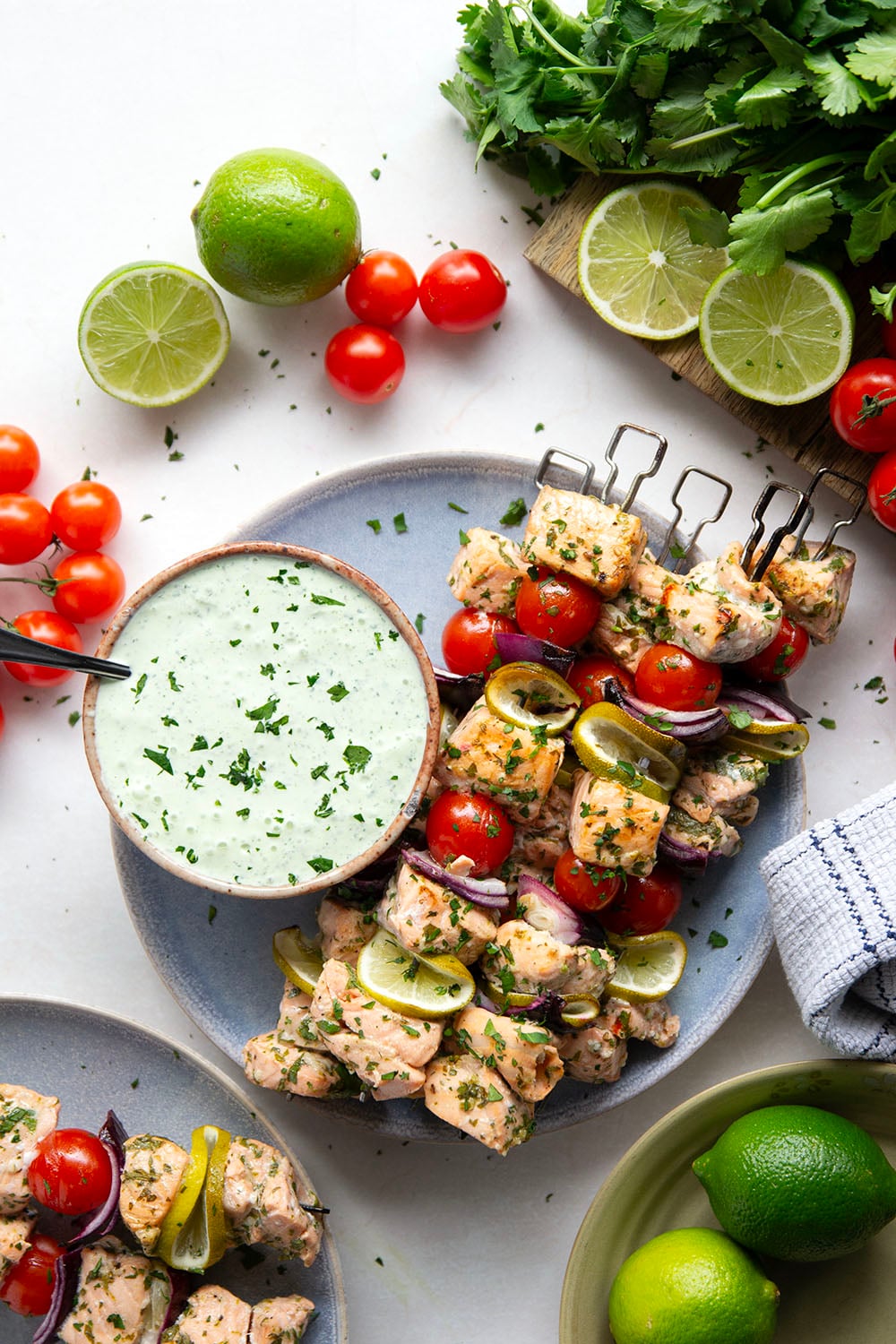 Marinated in a fresh cilantro lime sauce and grilled alongside red onion, cherry tomatoes, and served with a cilantro lime crema, these cilantro lime grilled salmon kabobs are a quick dinner to throw on the grill for any occasion.