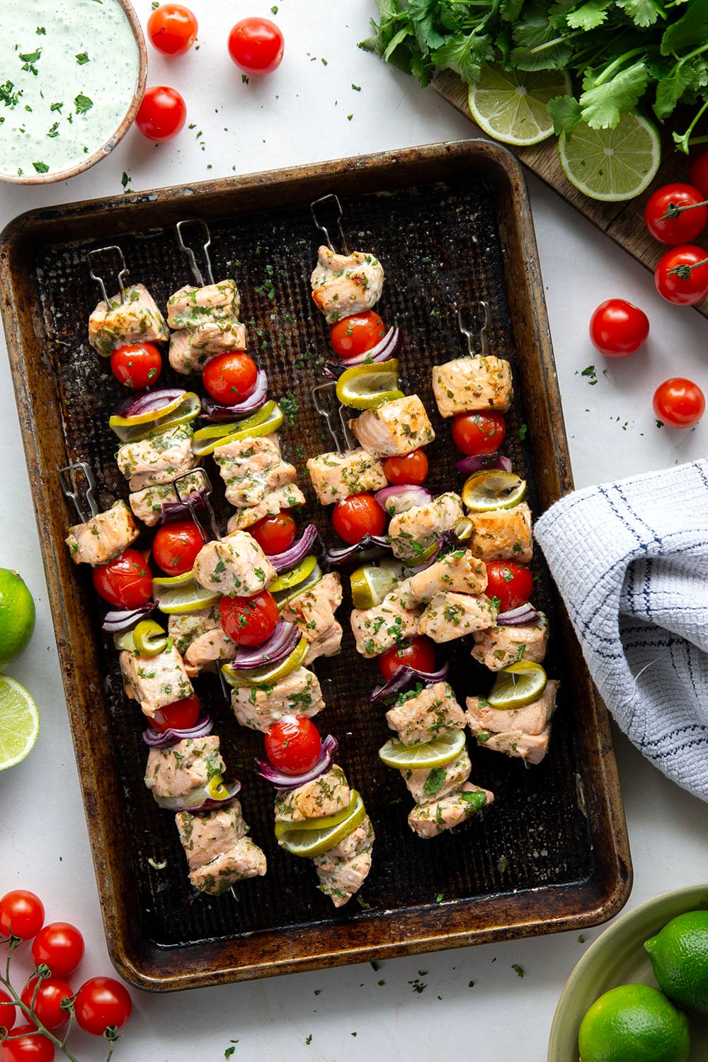 Marinated in a fresh cilantro lime sauce and grilled alongside red onion, cherry tomatoes, and served with a cilantro lime crema, these cilantro lime grilled salmon kabobs are a quick dinner to throw on the grill for any occasion.
