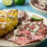 Spice-rubbed grilled flank steak and corn is an easy summer dish that pairs very well with a creamy chili lime sauce drizzled on top.