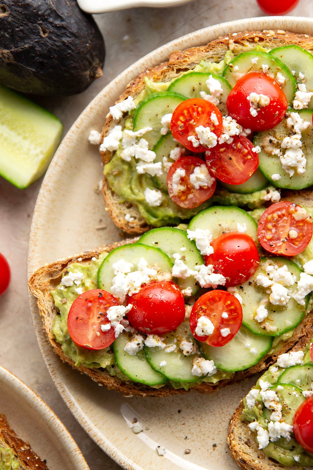 This Greek avocado toast is quick and easy enough for any kind of breakfast occasion! Pile toasted bread slices with silky mashed avocado, crisp cucumber slices, lots of fresh cherry tomatoes, and feta.