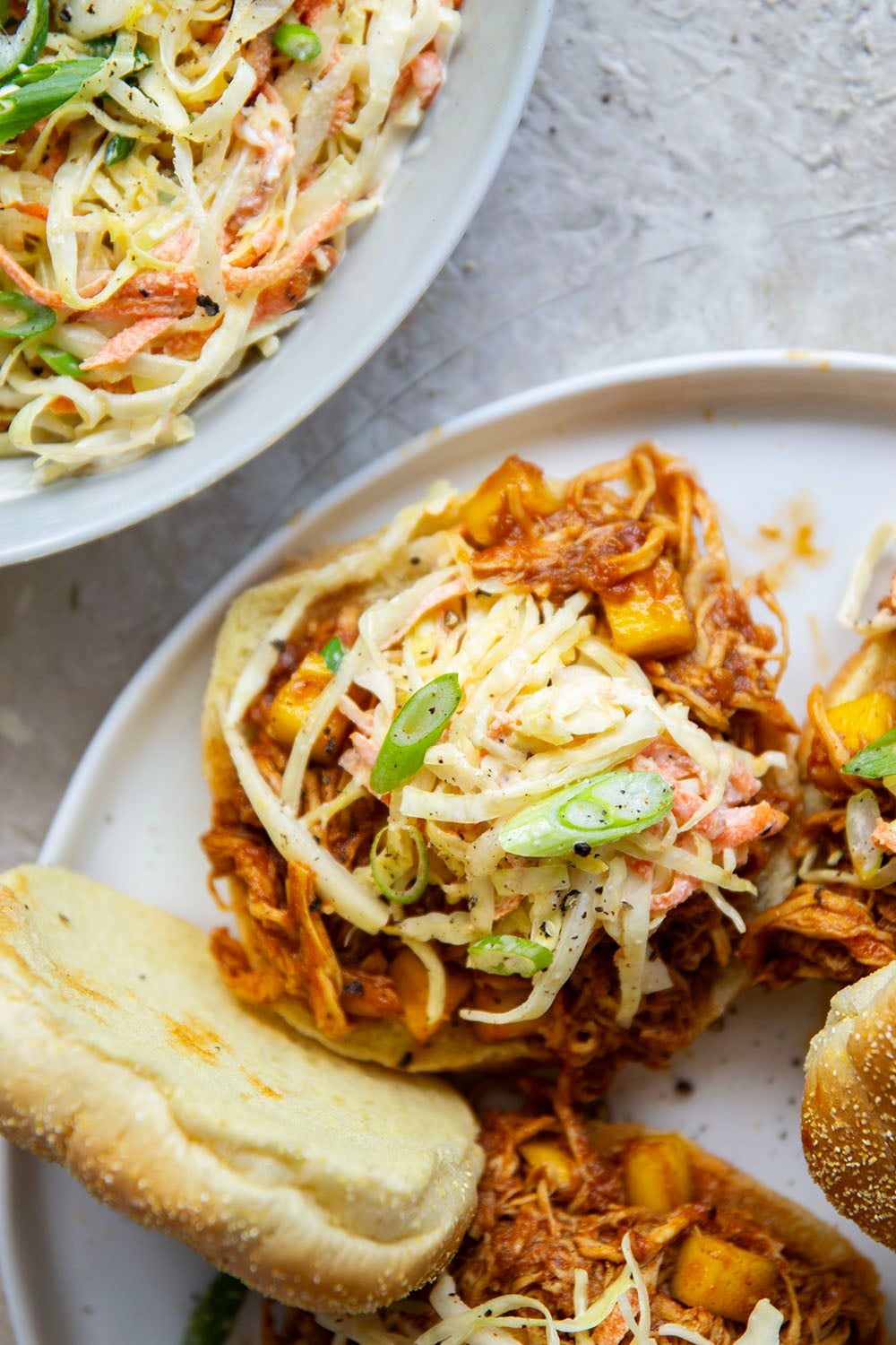 Slow cooked until perfectly fall-apart tender in lots of sweet mango and a homemade sauce, this pulled mango BBQ chicken makes the best summer sandwich with fresh slaw on top.
