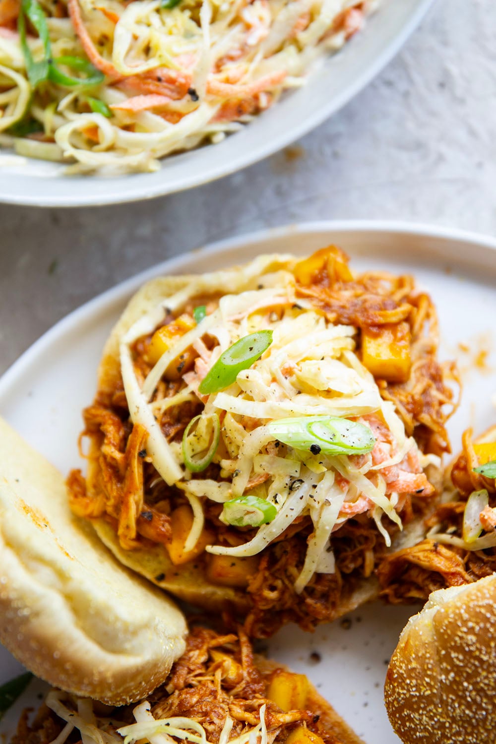 Slow cooked until perfectly fall-apart tender in lots of sweet mango and a homemade sauce, this pulled mango BBQ chicken makes the best summer sandwich with fresh slaw on top.