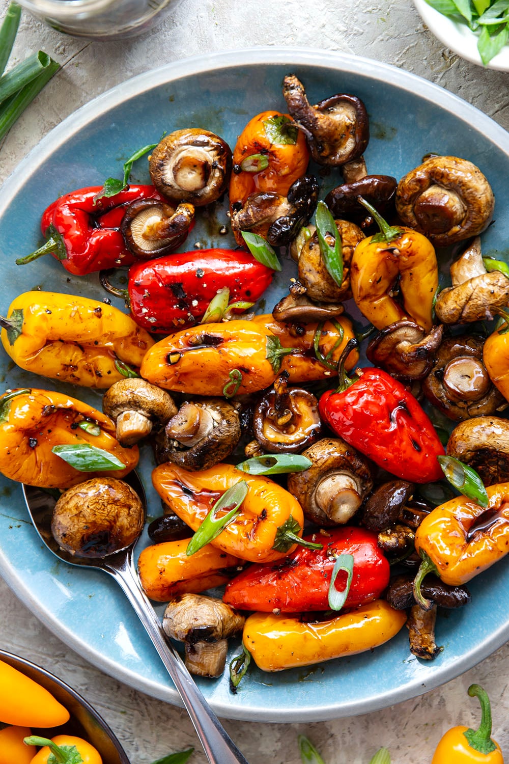 A mix of mushrooms and mini sweet peppers are marinated for hours in a flavorful soy marinade, grilled until tender and smoky, and topped with lots of green onions for an easy summer veggie side dish.