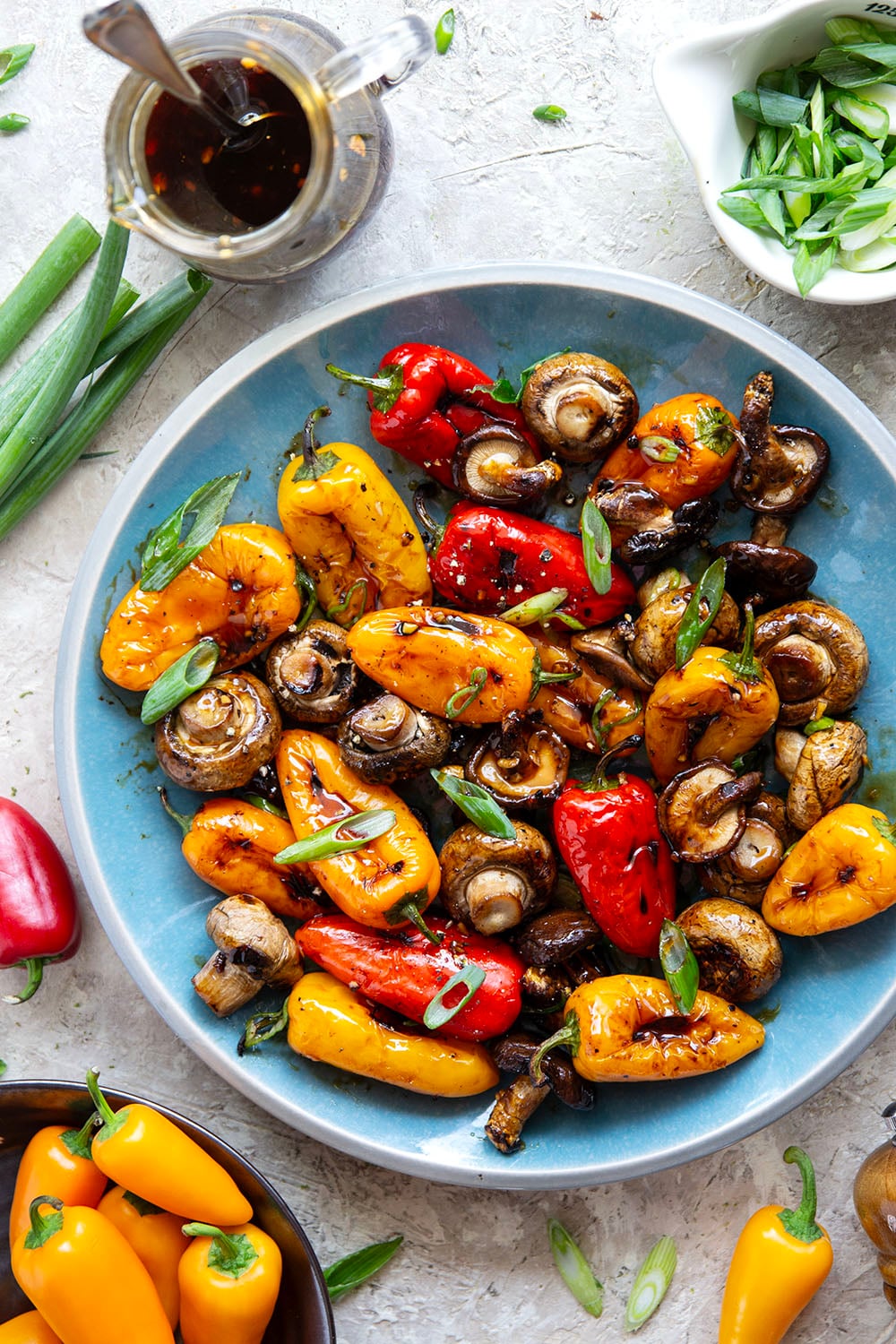 A mix of mushrooms and mini sweet peppers are marinated for hours in a flavorful soy marinade, grilled until tender and smoky, and topped with lots of green onions for an easy summer veggie side dish.