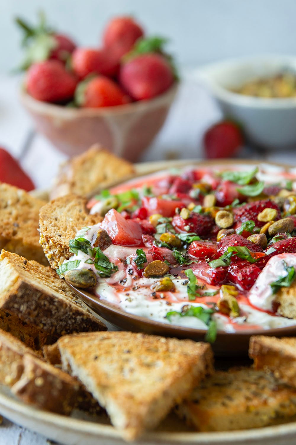 Silky whipped goat cheese is topped with juicy honey roasted strawberries and incredible served with crostini for dipping.