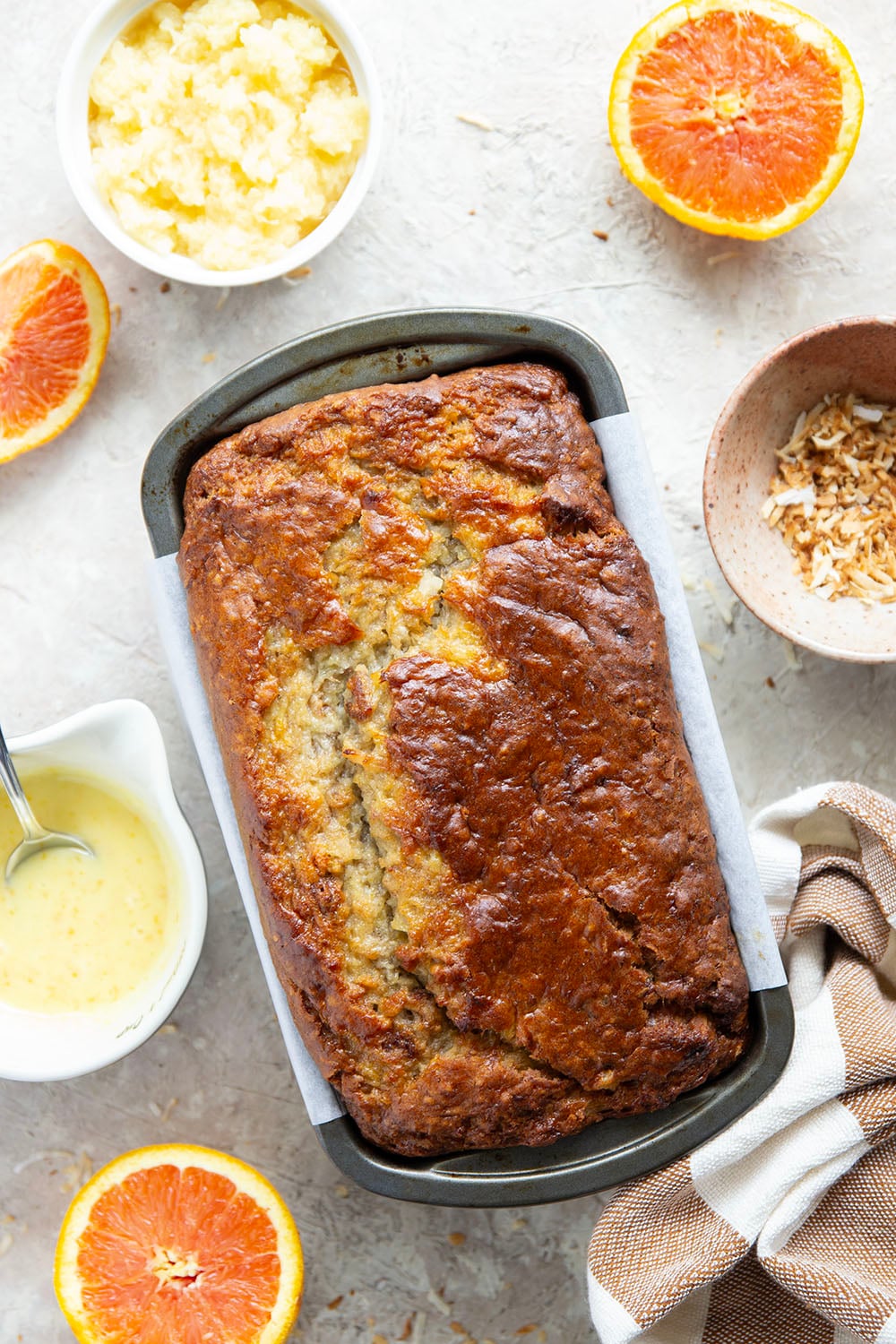 This tropical banana bread features a perfectly soft and dense texture and is packed with flaked coconut, lots of pineapple, and topped with a sweet citrus glaze.