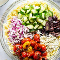 This colorful Greek orzo pasta salad is loaded with plenty of charred cherry tomatoes, crunchy cucumbers, lots of fresh feta, and tossed in a flavorful red wine vinaigrette for one stunning summer salad!
