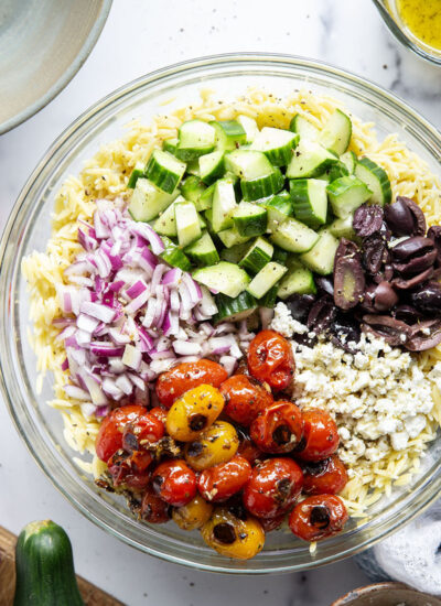 This colorful Greek orzo pasta salad is loaded with plenty of charred cherry tomatoes, crunchy cucumbers, lots of fresh feta, and tossed in a flavorful red wine vinaigrette for one stunning summer salad!