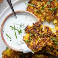 These yellow squash fritters feature perfectly crispy exteriors with a moist, flavorful texture inside. Serve them hot and crispy from the skillet with an herby fresh basil sour cream.