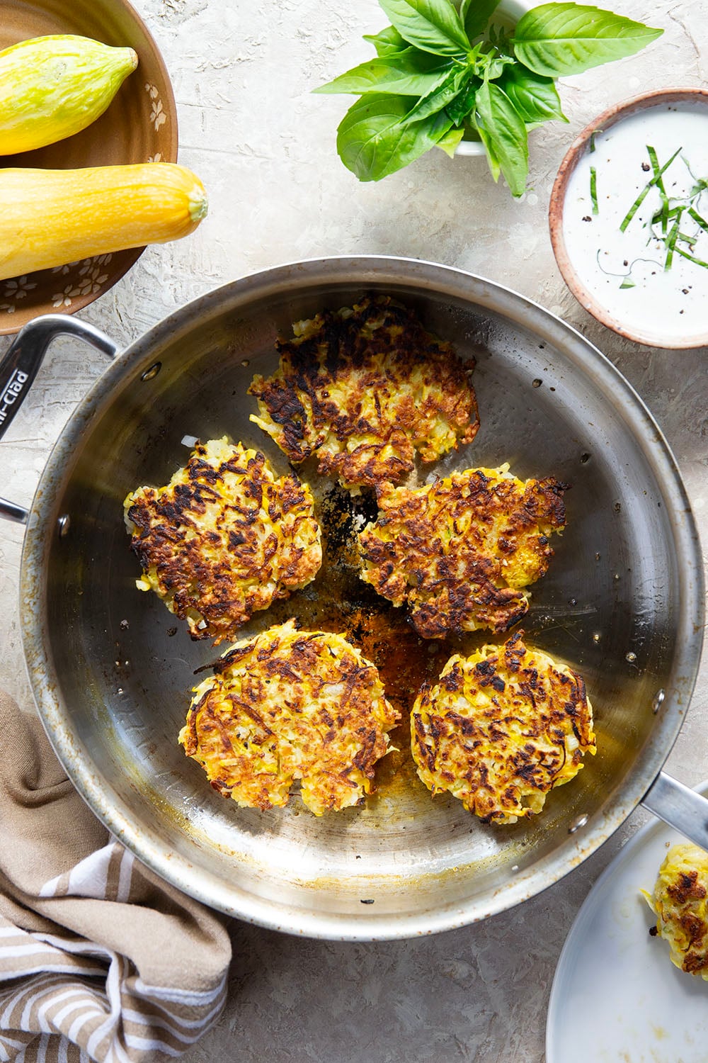 These yellow squash fritters feature perfectly crispy exteriors with a moist, flavorful texture inside. Serve them hot and crispy from the skillet with an herby fresh basil sour cream.