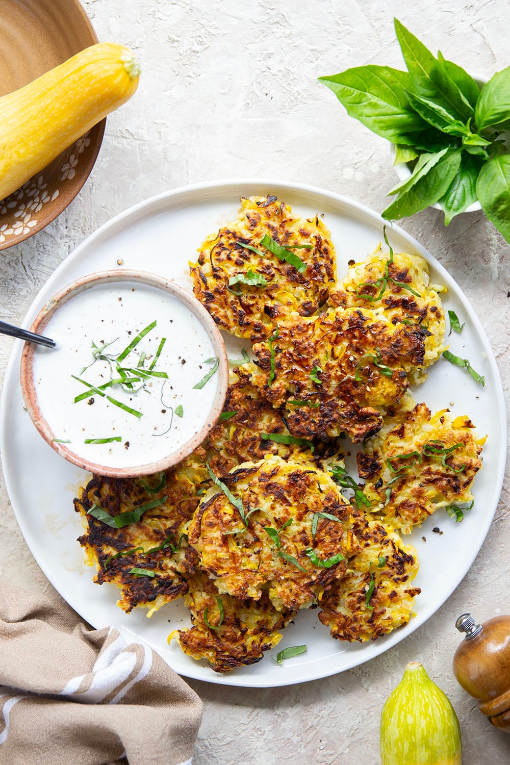 These yellow squash fritters feature perfectly crispy exteriors with a moist, flavorful texture inside. Serve them hot and crispy from the skillet with an herby fresh basil sour cream.