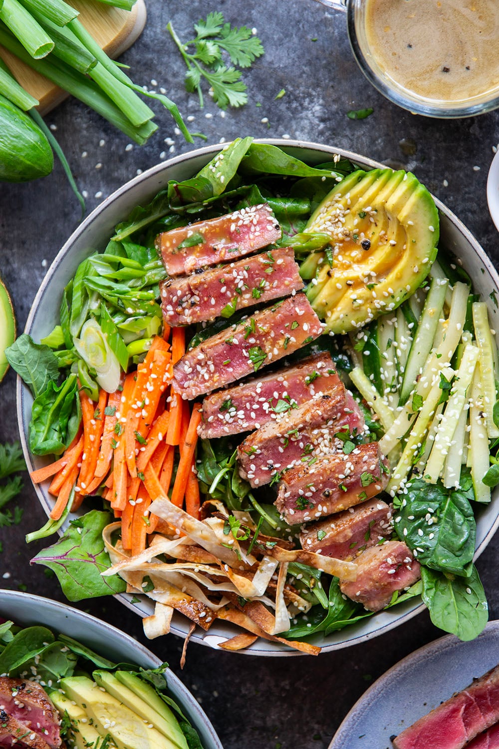 This seared ahi tuna salad features perfectly seared ahi tuna dressed up in bowls with lots of fresh greens, crunchy wonton strips, and a savory ginger soy dressing.