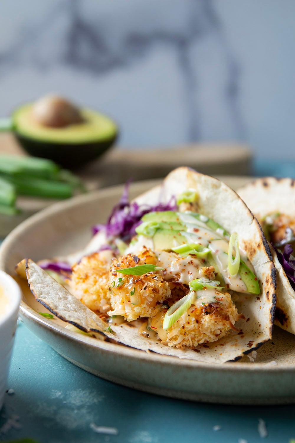 Golden oven-fried coconut shrimp collides with a sweet and spicy chili aioli, crisp cabbage, and lots of avocado in these loaded coconut shrimp tacos.