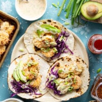 Golden oven-fried coconut shrimp collides with a sweet and spicy chili aioli, crisp cabbage, and lots of avocado in these loaded coconut shrimp tacos.