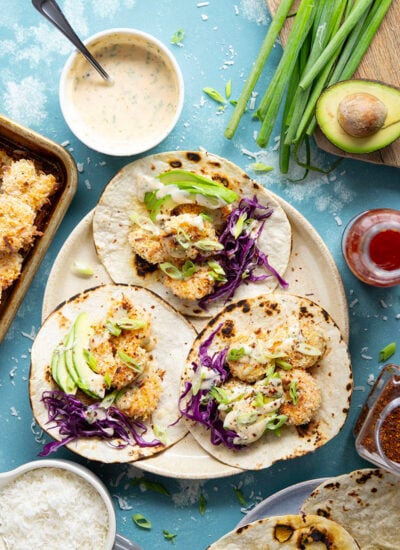 Golden oven-fried coconut shrimp collides with a sweet and spicy chili aioli, crisp cabbage, and lots of avocado in these loaded coconut shrimp tacos.