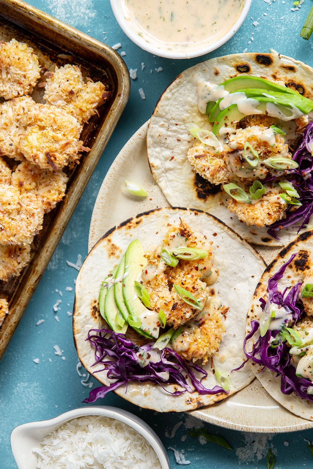 Golden oven-fried coconut shrimp collides with a sweet and spicy chili aioli, crisp cabbage, and lots of avocado in these loaded coconut shrimp tacos.