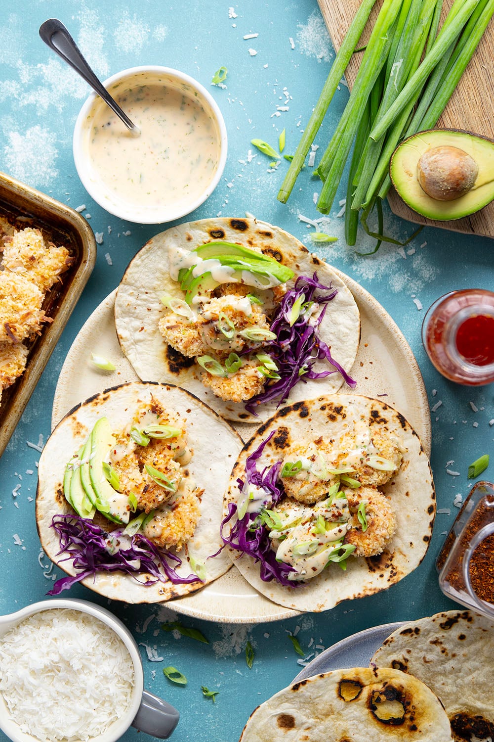 Golden oven-fried coconut shrimp collides with a sweet and spicy chili aioli, crisp cabbage, and lots of avocado in these loaded coconut shrimp tacos.