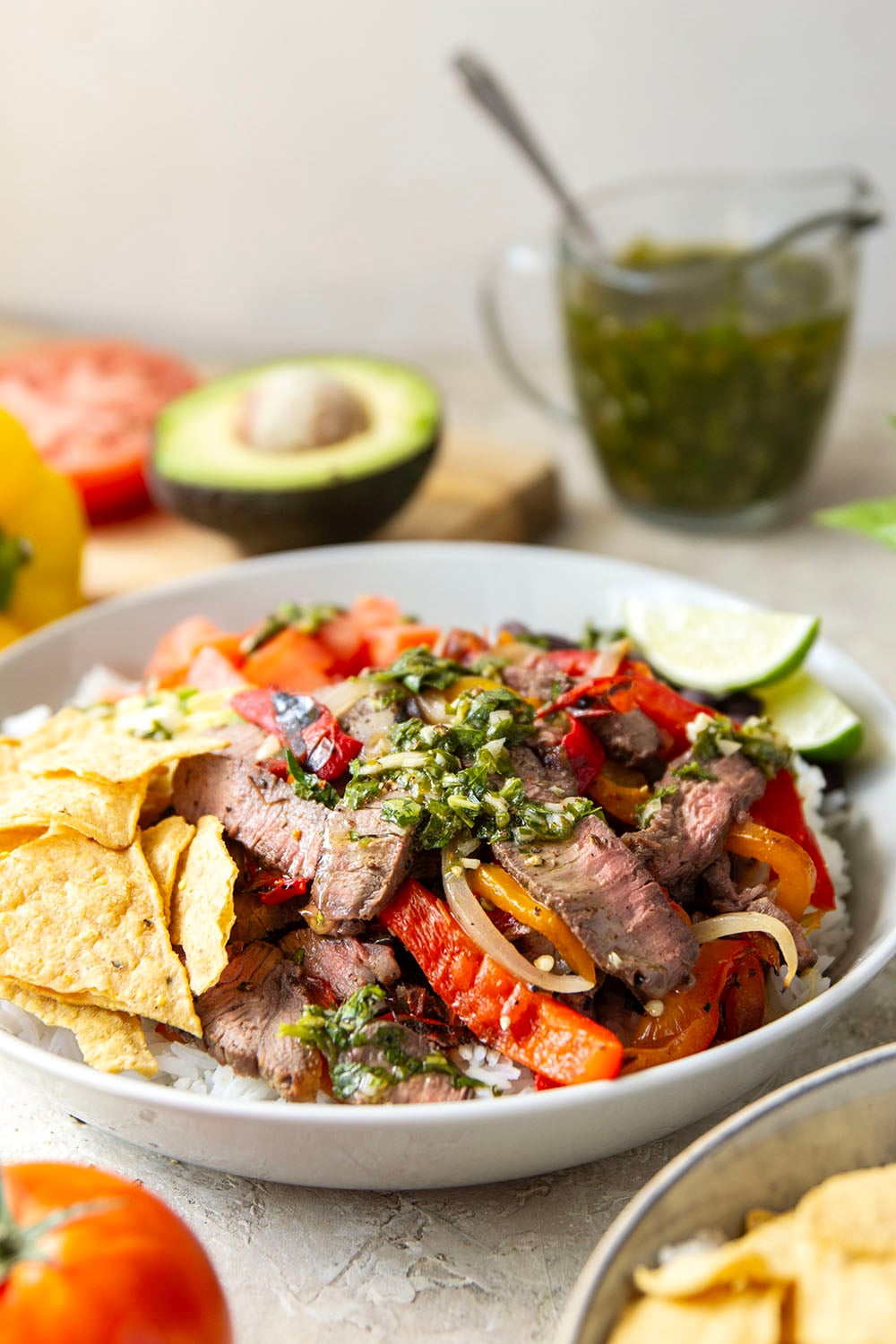 Juicy grilled sirloin steak, sweet peppers, and an herby fresh chimichurri sauce make for the ultimate summer steak fajita bowls.