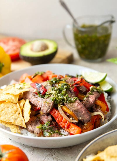 Juicy grilled sirloin steak, sweet peppers, and an herby fresh chimichurri sauce make for the ultimate summer steak fajita bowls.
